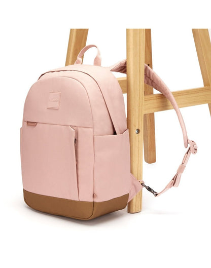 Pacsafe® Go 15L Anti-theft Backpack, sunset pink with tan bottom gusset, with one strap secured to chair leg