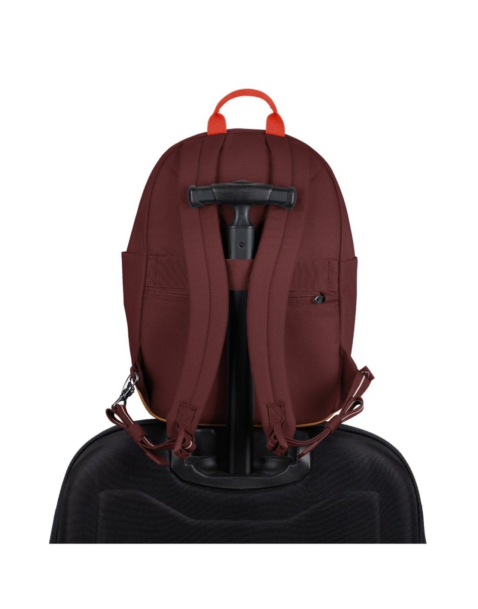 Pacsafe® Go 15L Anti-theft Backpack in garnet red secured onto the extended handle of a full sized wheeled luggage