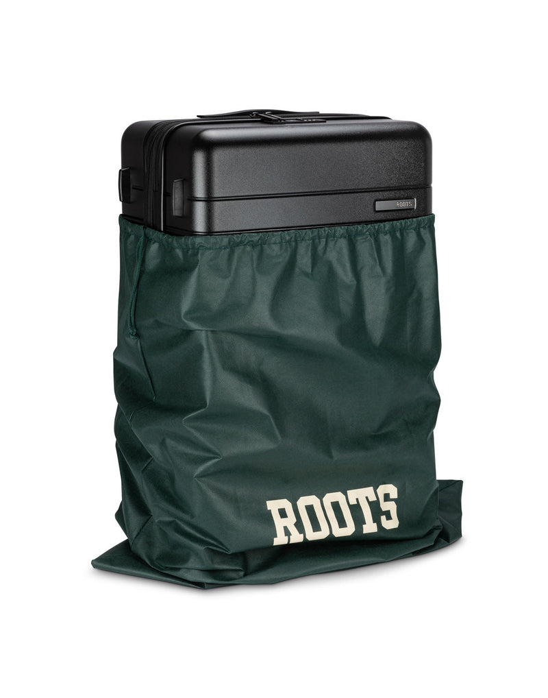 Front angle view of Roots Travel 24" Expandable Hardside Spinner in black, placed inside a Roots bag.