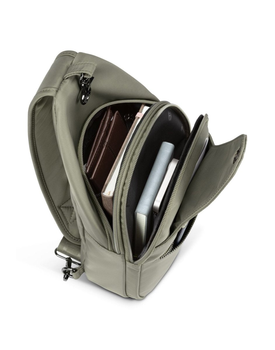 Top view of unzipped Roots Travel Sling Bag in sage, with items found inside interior compartments.