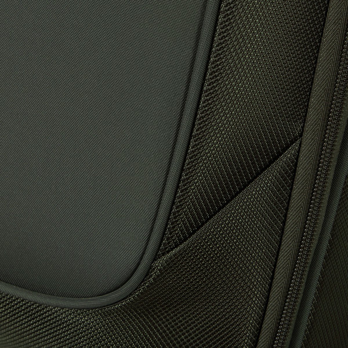 Close-up of green textured fabric, seams, and zipper on a Samsonite Re-Lite Spinner Medium luggage.