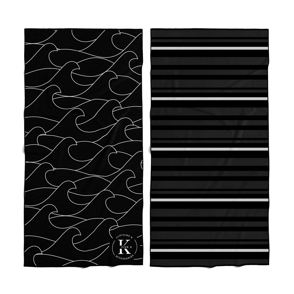 Two K5 Microfibre Beach Towels: one black with a white wave, the other black with gray stripes.