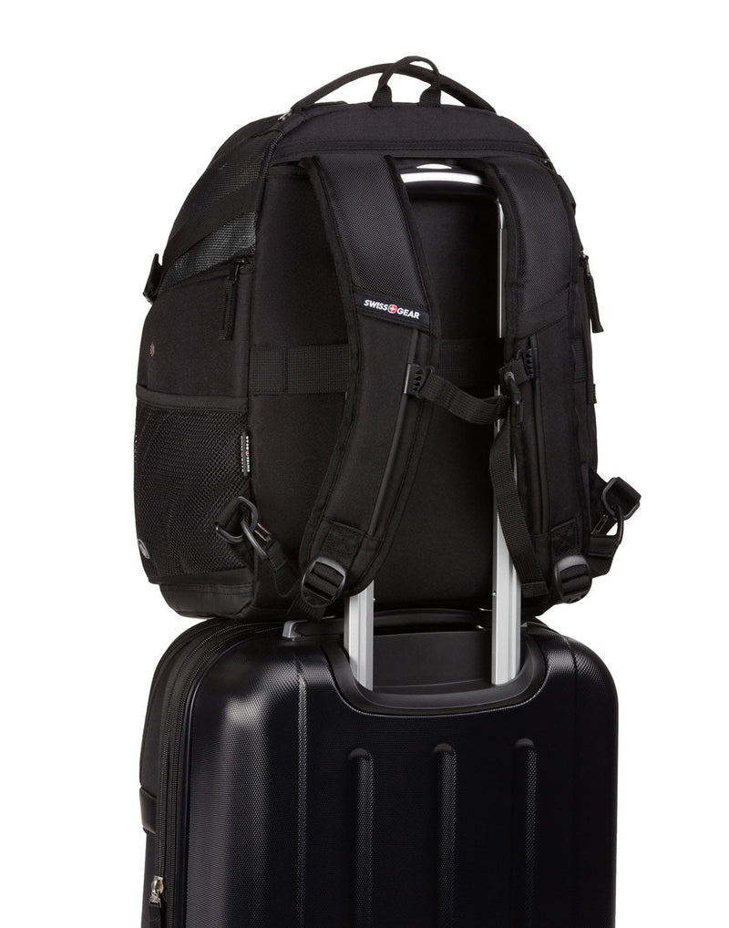 Swiss Gear Premium Pet Backpack on top of black luggage with back strap through telescopic luggage handle