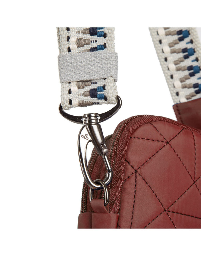 Close up of woven guitar strap style crossbody strap with silver metal clip to detach strap from bag