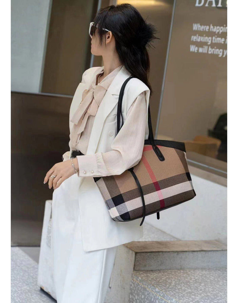 Woman outside wearing a white pant suit with Alina's Rounded Handbag in black on one shoulder.