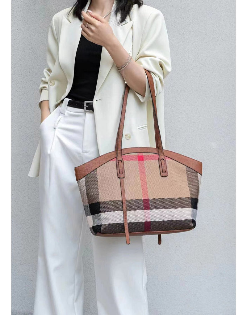 Woman wearing white pant suit with Alina's Rounded Handbag in brown slung on her arm at the elbow