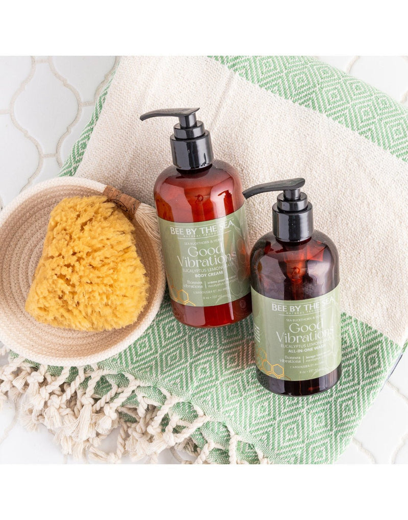 Two Good Vibrations pump bottles on a natural and green towel with a natural sponge beside