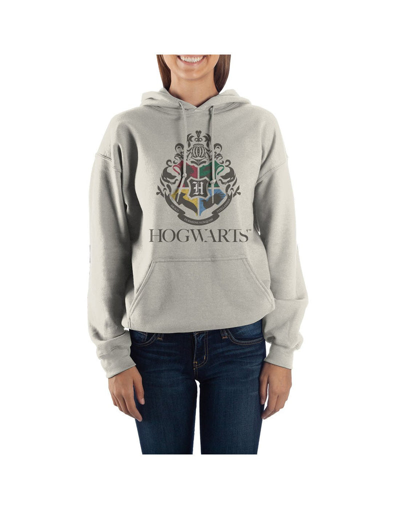 Woman wearing dark blue jeans and Harry Potter light grey unisex hoodie with Hogwarts crest and school name