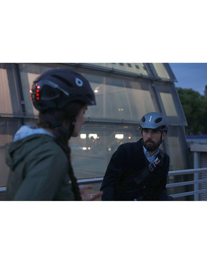 Two people wearing Briko E-One LED Reflective Bike Helmes with front white and back red lights turned on