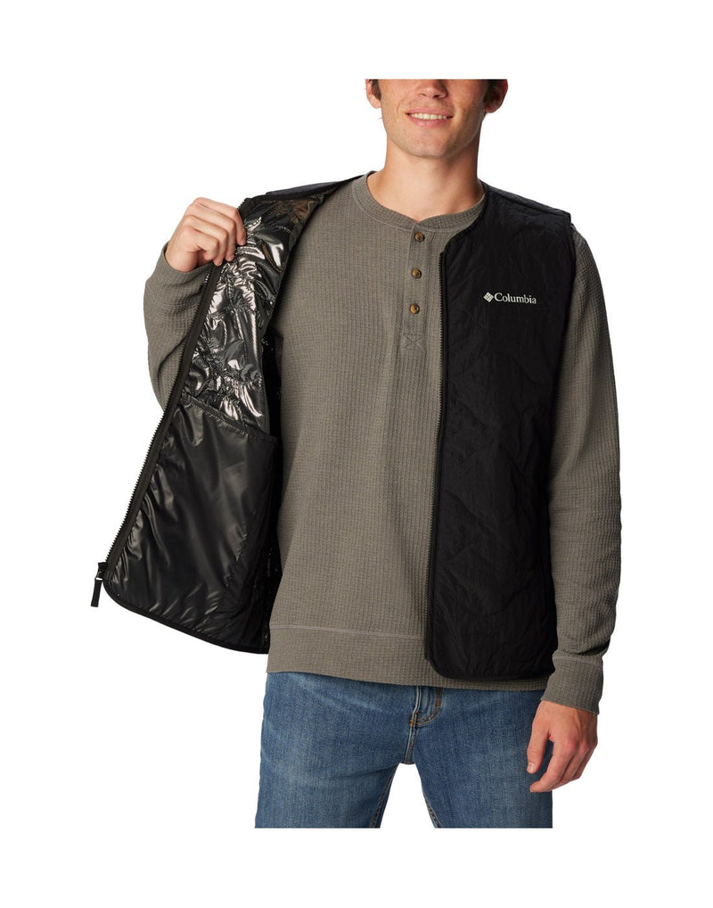 Front view of a man wearing the Columbia Men's Birchwood™ Vest in black colour.  Unzipped and showing the jacket's Omni-Heat™ thermal reflective lining.