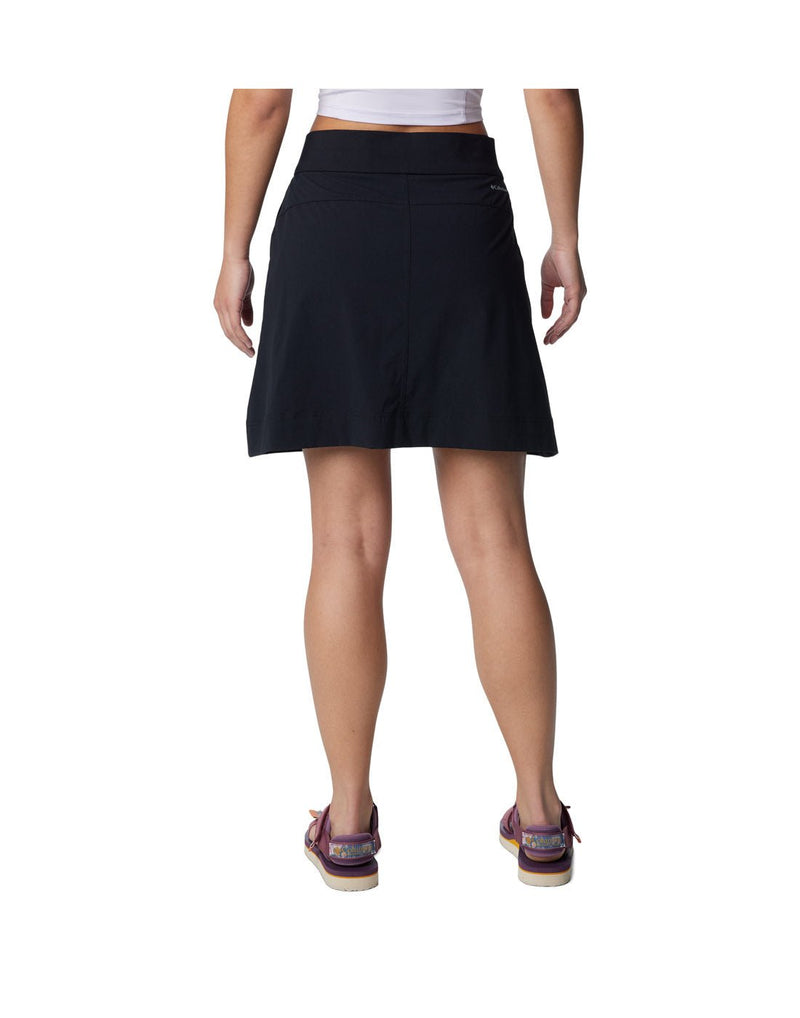Bottom half of woman wearing purple sandals and Columbia Women's Anytime™ Straight Skort in black, back view