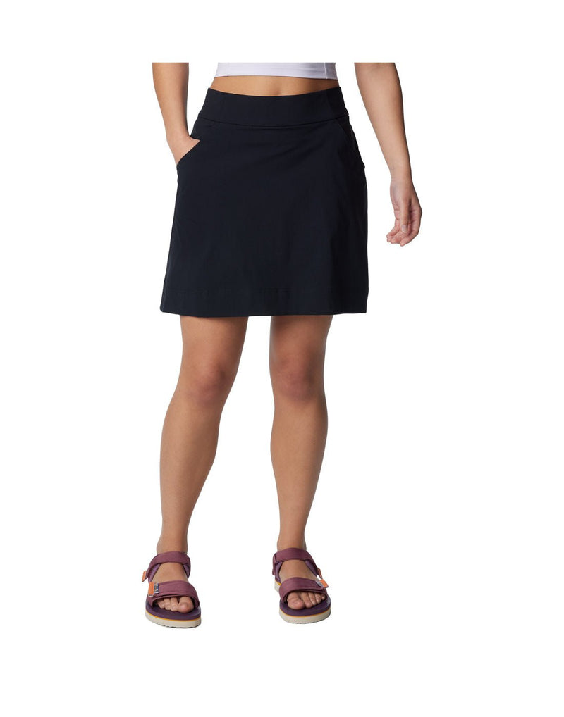 Bottom half of woman wearing purple sandals and Columbia Women's Anytime™ Straight Skort in black with one hand in pocket, front view