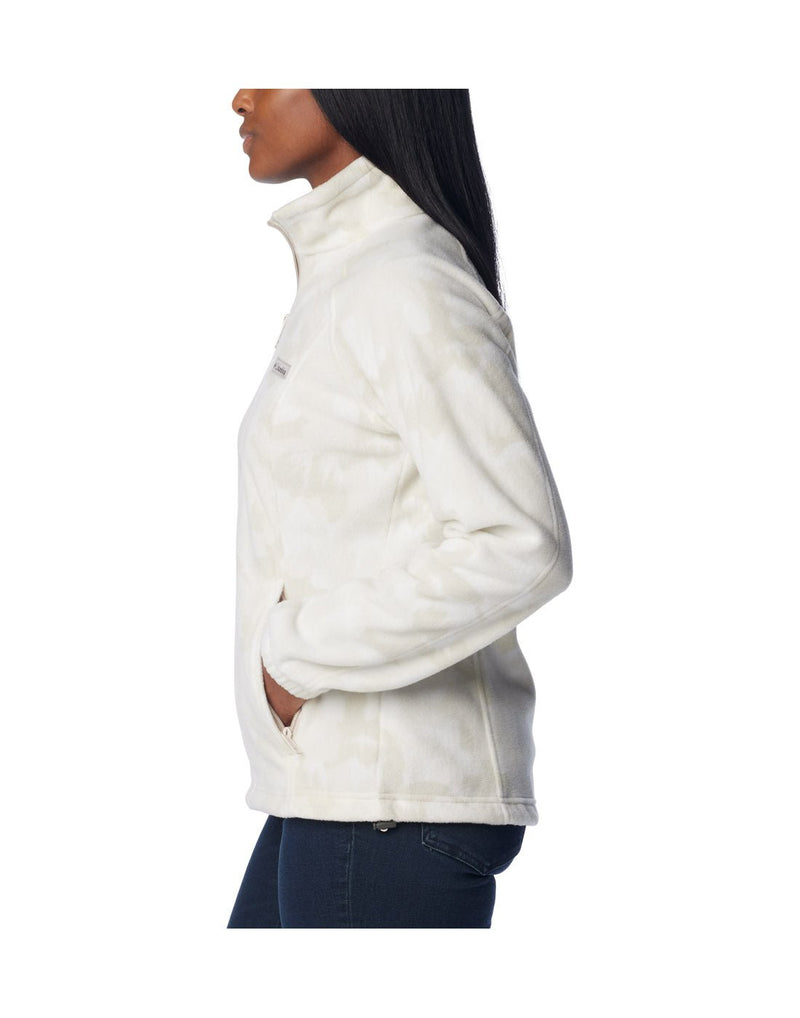 Woman wearing dark blue jeans and Columbia Women's Benton Springs™ Printed Full Zip Fleece Jacket in dark stone peonies, white with light beige floral pattern, side view with hands in pockets