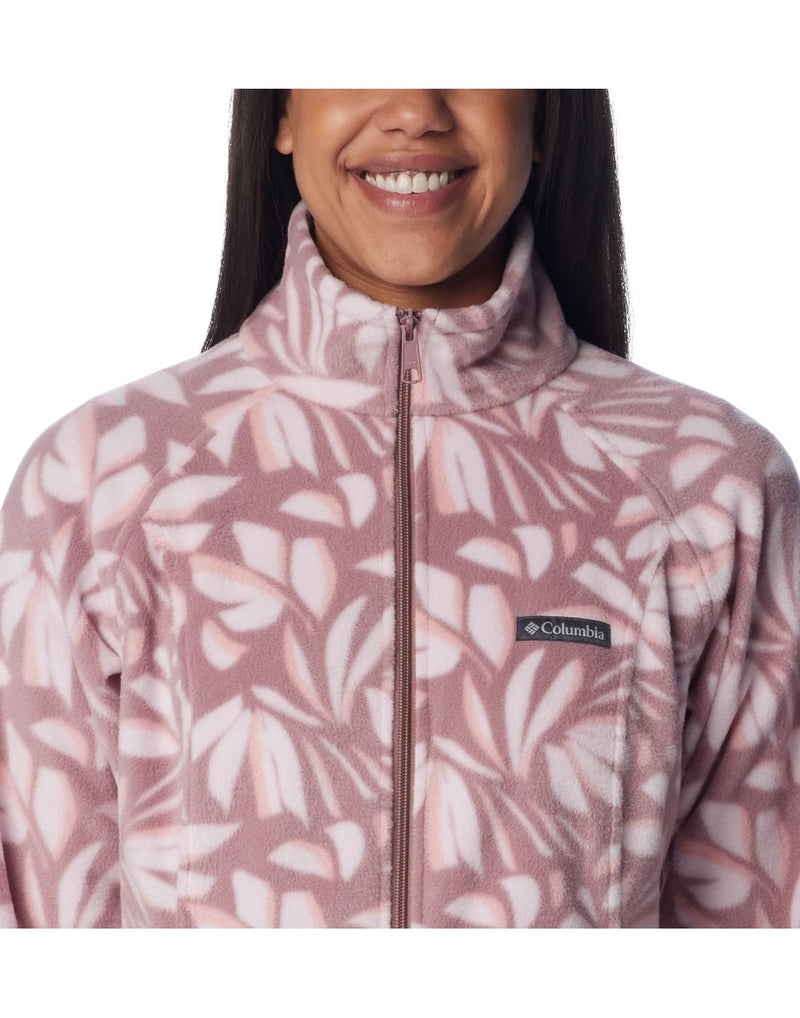 Close up of woman wearing Columbia Women's Benton Springs™ Printed Full Zip Fleece Jacket in fig areca pattern, front view, zipped up with Columbia logo on left chest