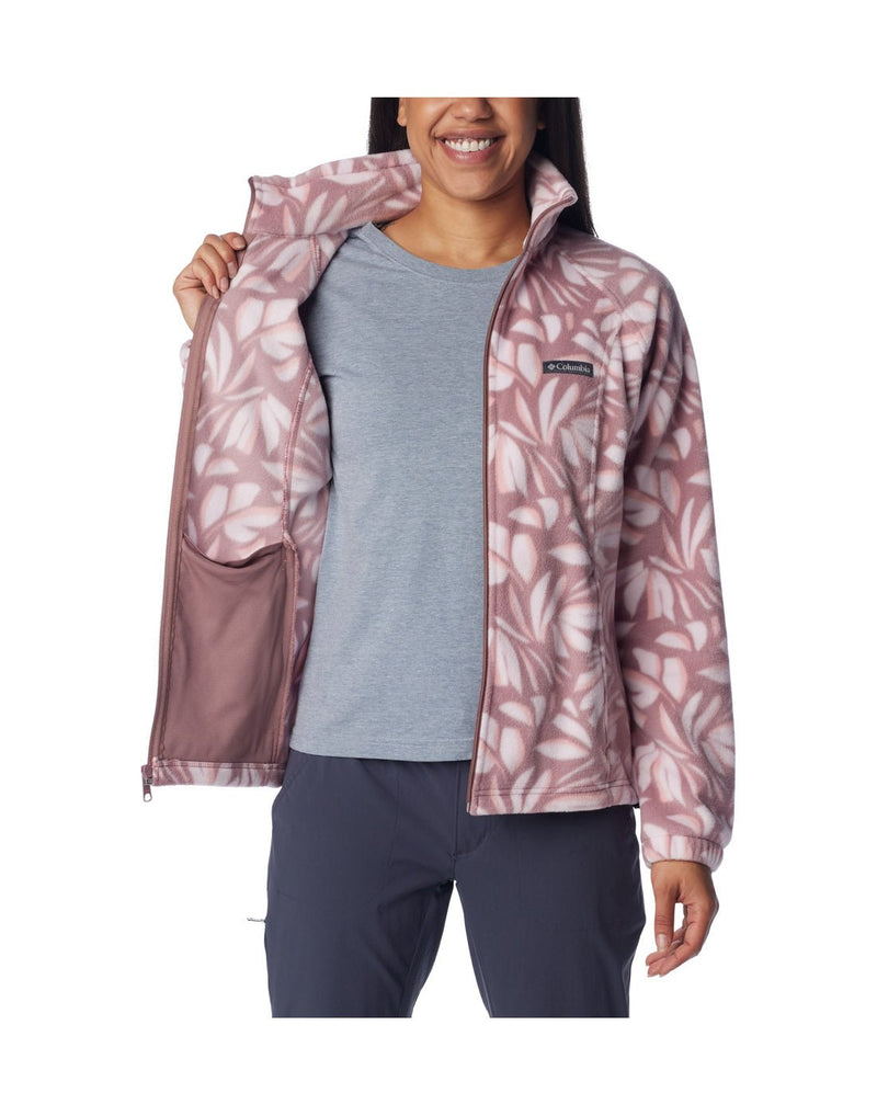 Woman wearing Columbia Women's Benton Springs™ Printed Full Zip Fleece Jacket in fig areca pattern, front view, unzipped, with grey t-shirt beneath, holding one side of jacket open to show interior