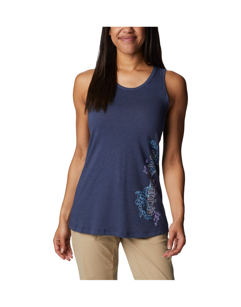 Woman wearing light khaki pants and Columbia Women's Bluff Mesa™ Tank in nocturnal heather, indigo colour with floral pattern on one side, front view