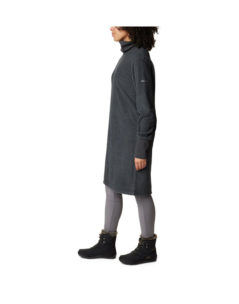 Left side view of a woman wearing a Columbia Women's Boundless Trek™ Fleece Dress in black.  Columbia logo on left sleeve.