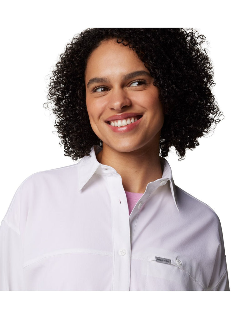 Close up of woman wearing Columbia Women's Boundless Trek™ Layering Long Sleeve Shirt in white, with Columbia logo on left chest pocket