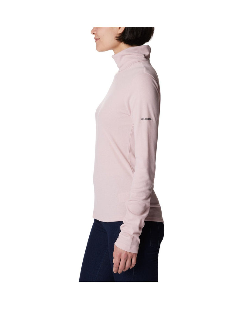 Left side view of a woman wearing the Columbia Women's Boundless Trek™ Ribbed Turtleneck Long Sleeve Shirt in Dusty Pink.