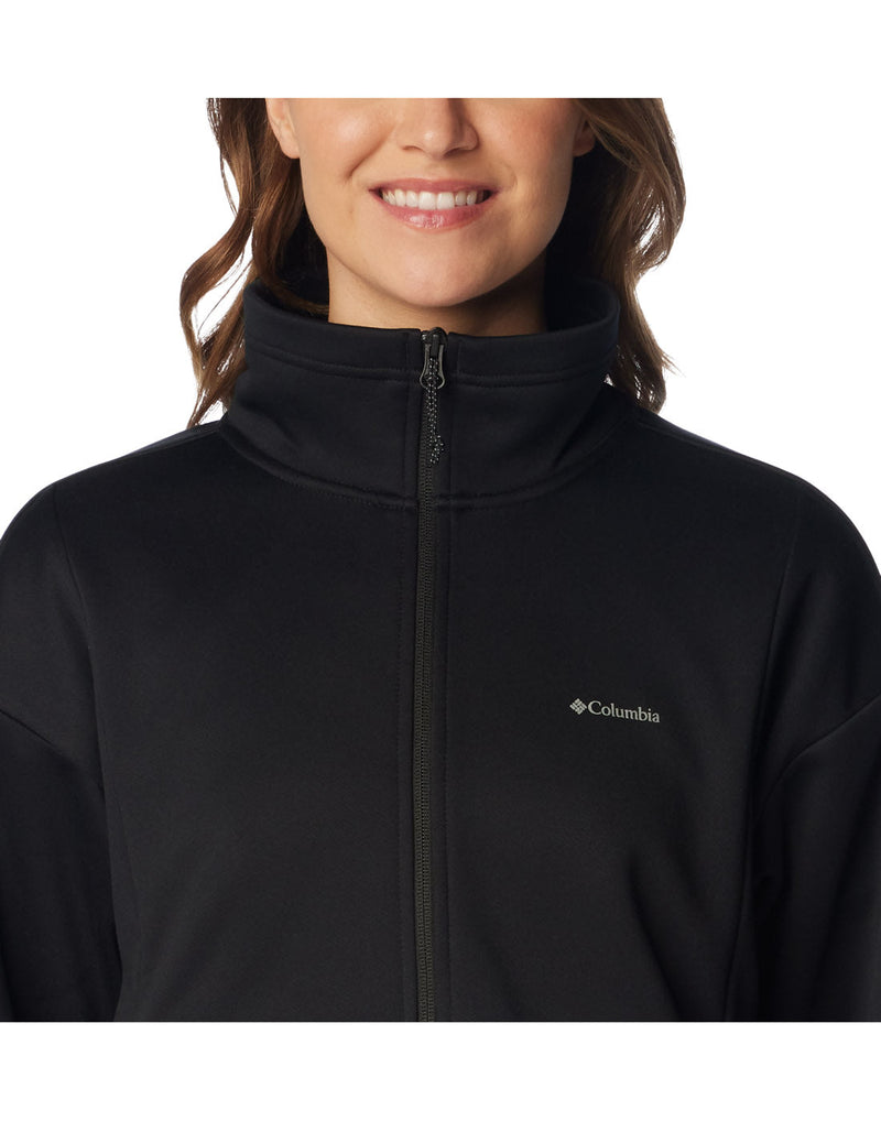 Close up of woman wearing Columbia Women's Boundless Trek™ Tech Full Zip Jacket in black, front view, zipped up with Columbia logo on left chest