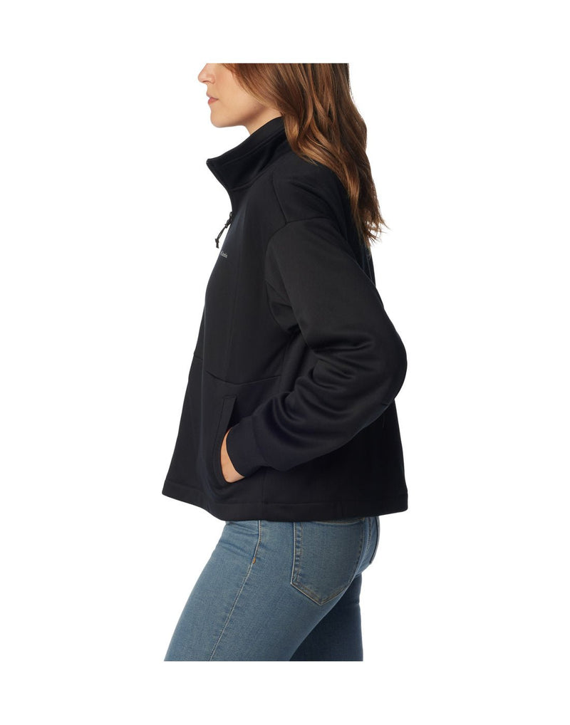 Woman wearing blue jeans and Columbia Women's Boundless Trek™ Tech Full Zip Jacket in black, side view with hands in pockets