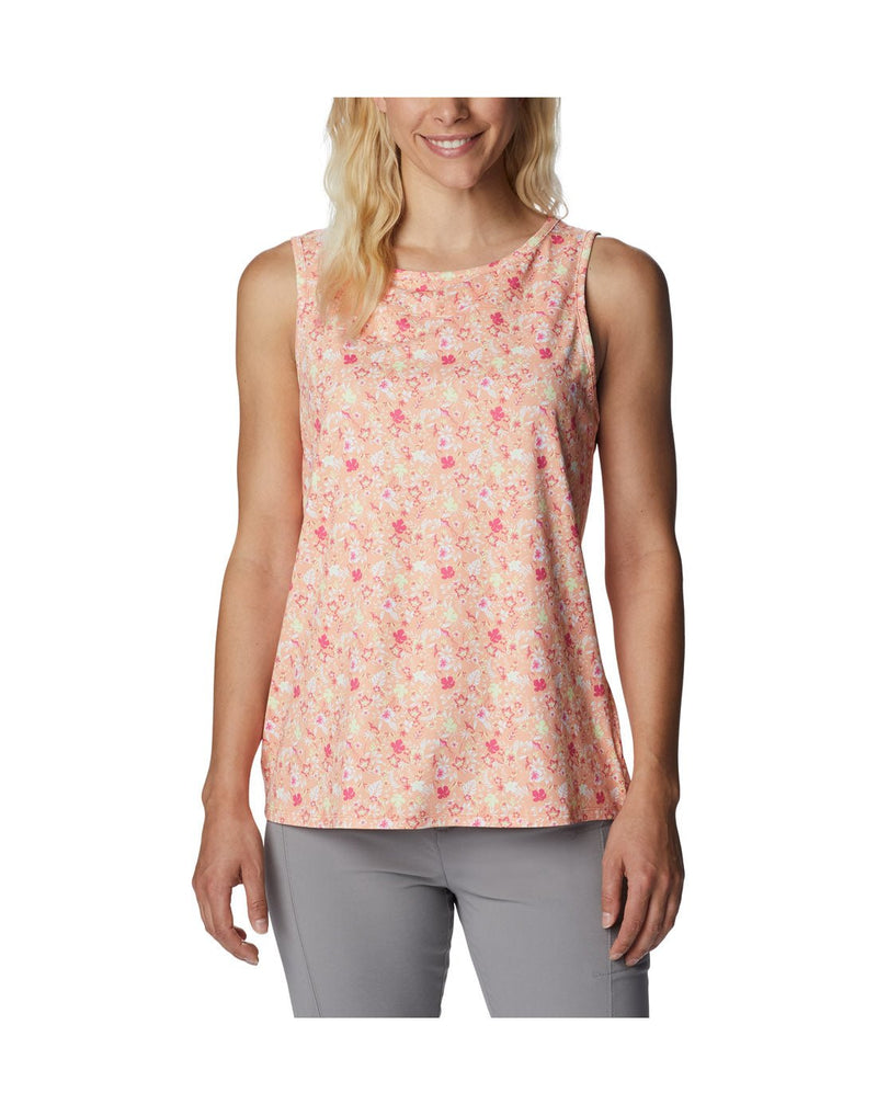 Woman wearing light grey pants and Columbia Women's Chill River™ Tank in peach mini hibiscus, front view