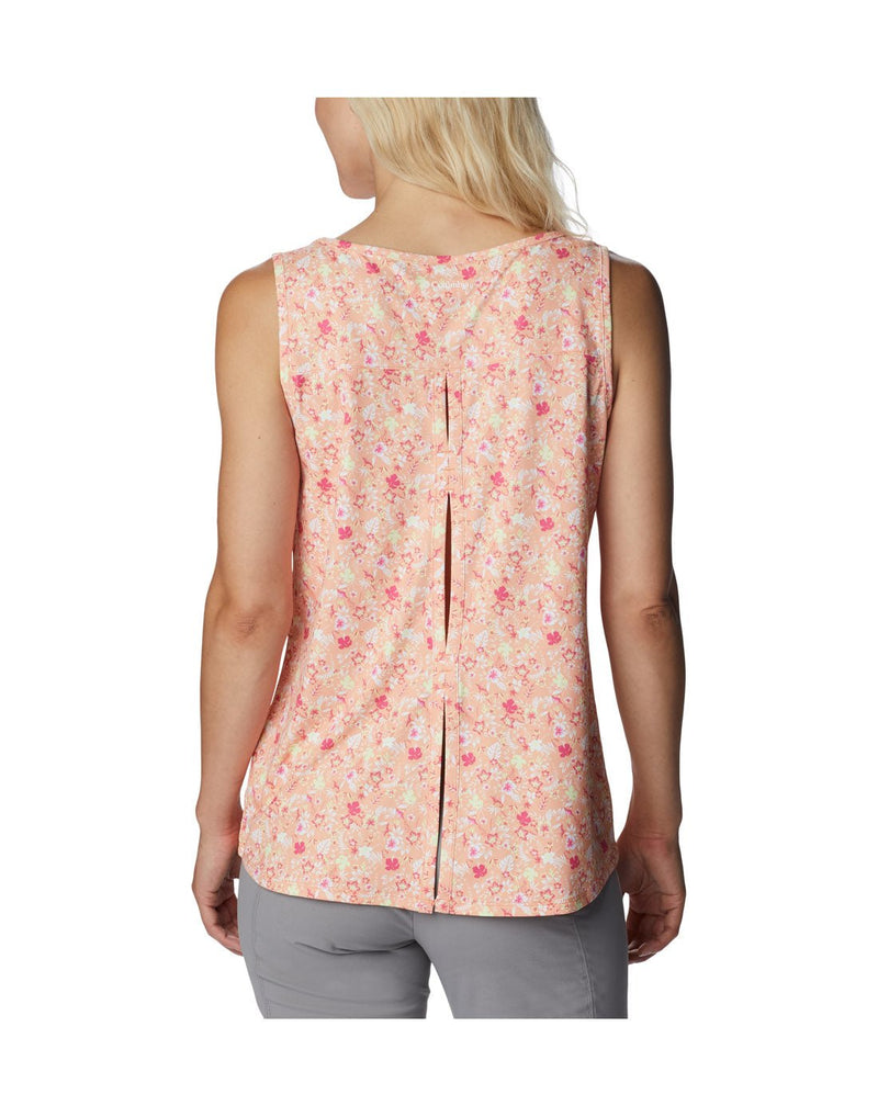 Woman wearing light grey pants and Columbia Women's Chill River™ Tank in peach mini hibiscus, back view with pleated slit down center of back