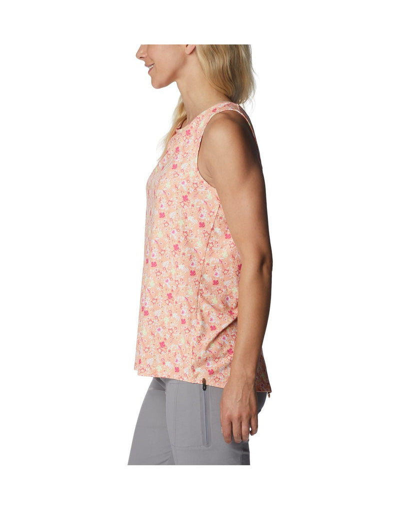 Woman wearing light grey pants and Columbia Women's Chill River™ Tank in peach mini hibiscus, side view