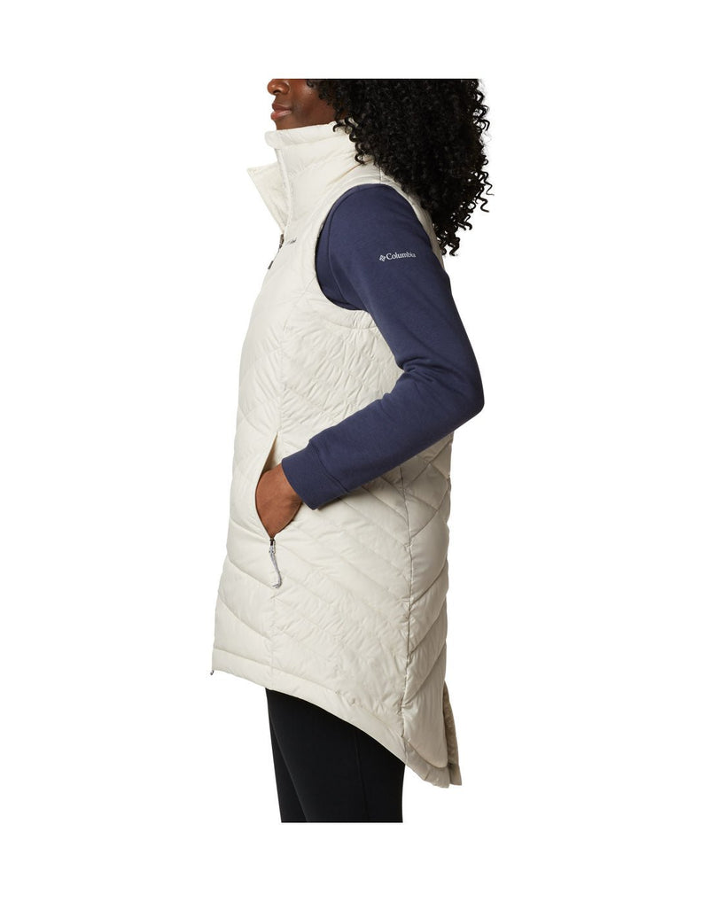 Left side view of a woman wearing a Columbia Women's Heavenly™ Long Vest in Chalk colour, hand in side pocket.