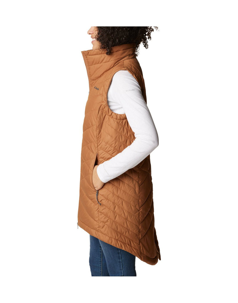 Left side view of a woman wearing a Columbia Women's Heavenly™ Long Vest in Camel Brown colour, with hand in side pocket.