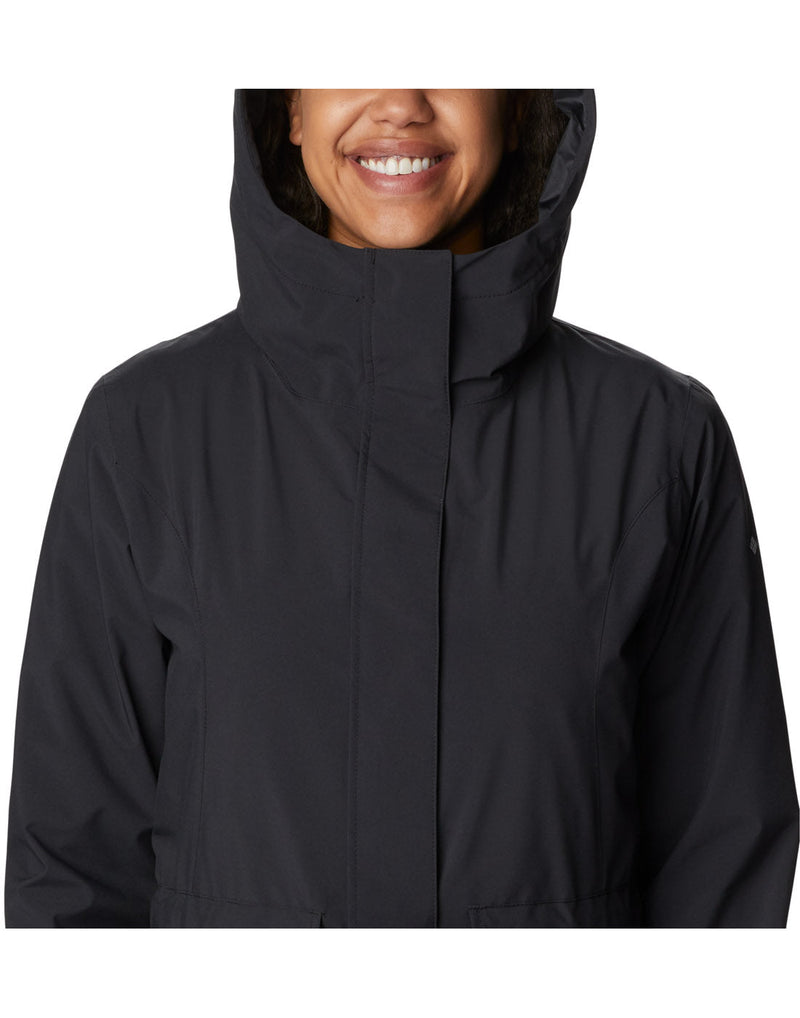 Close up of torso of woman wearing Columbia Women's Here and There™ II Rain Trench in black, front view, zipped up and hood up