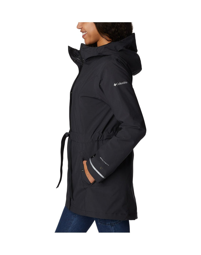 Woman wearing Columbia Women's Here and There™ II Rain Trench in black, side view with hands in pockets