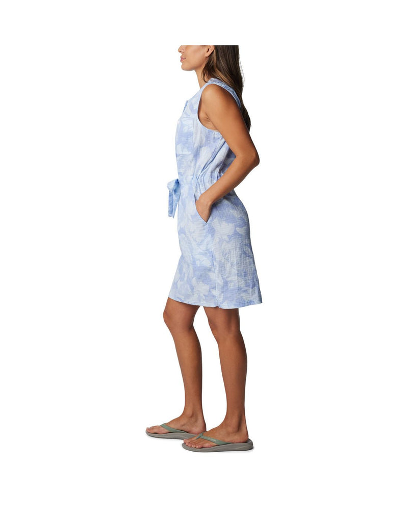 Woman wearing Columbia Women's Holly Hideaway™ Breezy Dress in whisper peonies, blue with white pattern, side view with hands in pockets