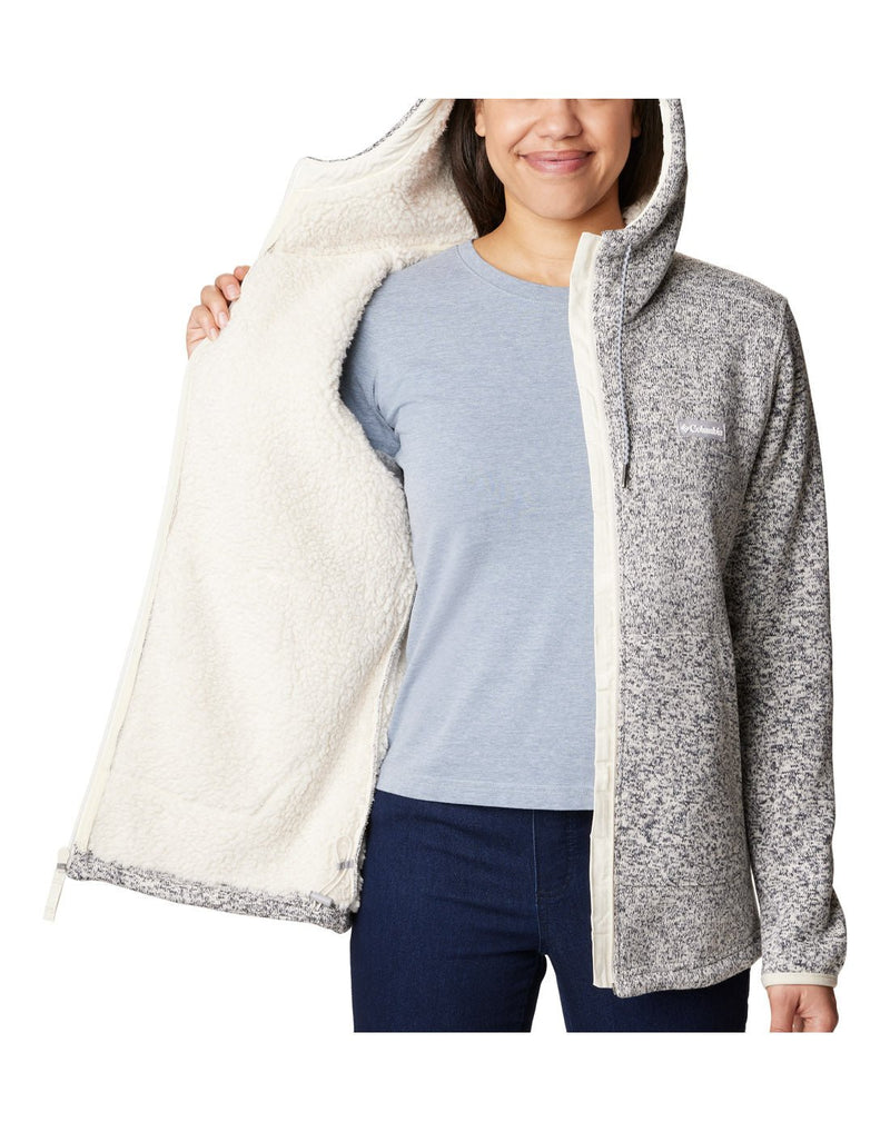 Front view of a woman wearing the Columbia Women's Sweater Weather™ Sherpa Full Zip Hooded Jacket in Chalk Heather colour, hood up.  Unzipped with front panel open showing the interior Sherpa lining.