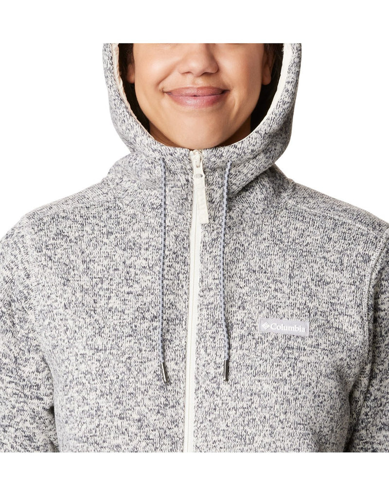 Close-up front view of a woman wearing the Columbia Women's Sweater Weather™ Sherpa Full Zip Hooded Jacket in Chalk Heather colour, hood up.