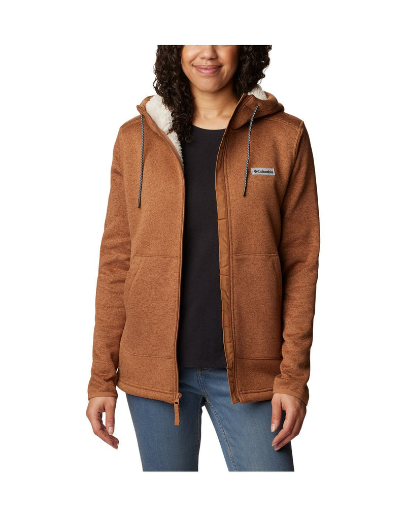 Front view of a woman wearing the Columbia Women's Sweater Weather™ Sherpa Full Zip Hooded Jacket in Camel Brown Heather colour, hood down, unzipped.