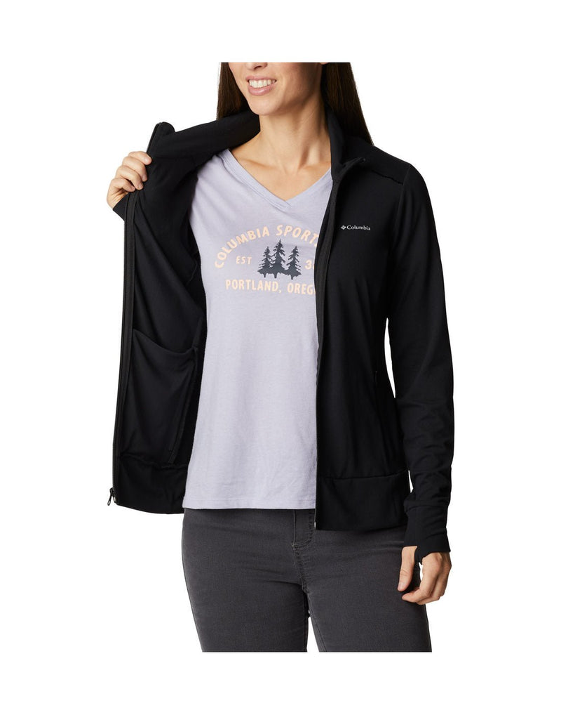 Woman wearing black jeans, light blue t-shirt and Columbia Women's Weekend Adventure™ Full Zip Jacket in black, unzipped, holding one side open to show interior, front view