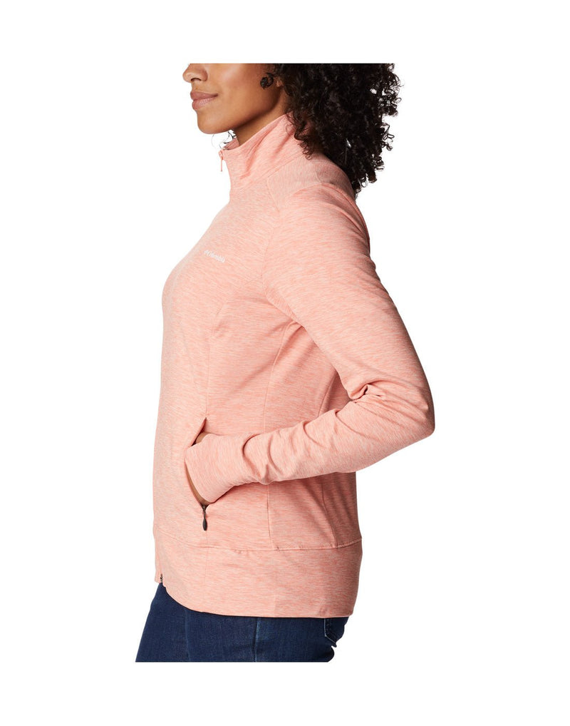 Woman wearing blue jeans and Columbia Women's Weekend Adventure™ Full Zip Jacket in peach heather, zipped up, side view with hands in pockets