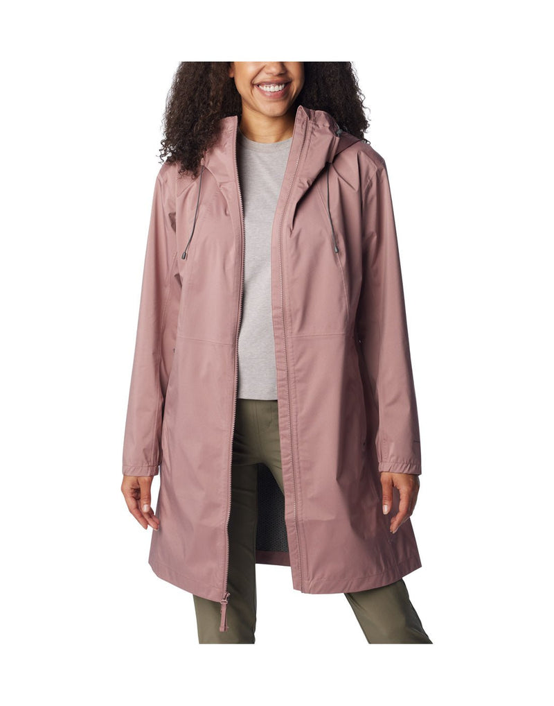 Woman wearing green pants, grey shirt, and Columbia Women's Weekend Adventure™ Long Shell Jacket in fig, unzipped, front view