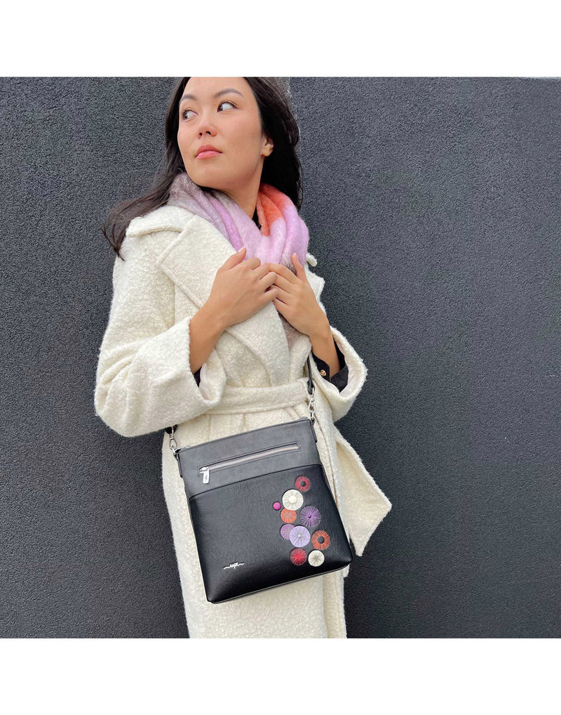 Woman outside wearing white trench coat and Espe Floret Crossbody in black