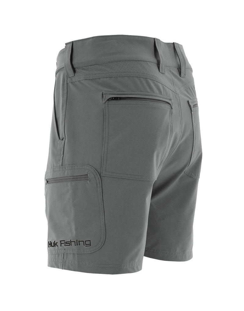 Back angled view of Huk Men's Next Level 7 inch Short in Charcoal Grey colour. Shows the cargo pocket on left leg of the shorts and zippered back pockets.