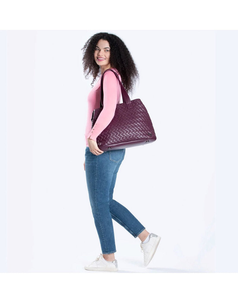 Woman wearing pink top and blue jeans with the Lug Tempo VL Tote Bag in wine red slung on her left shoulder
