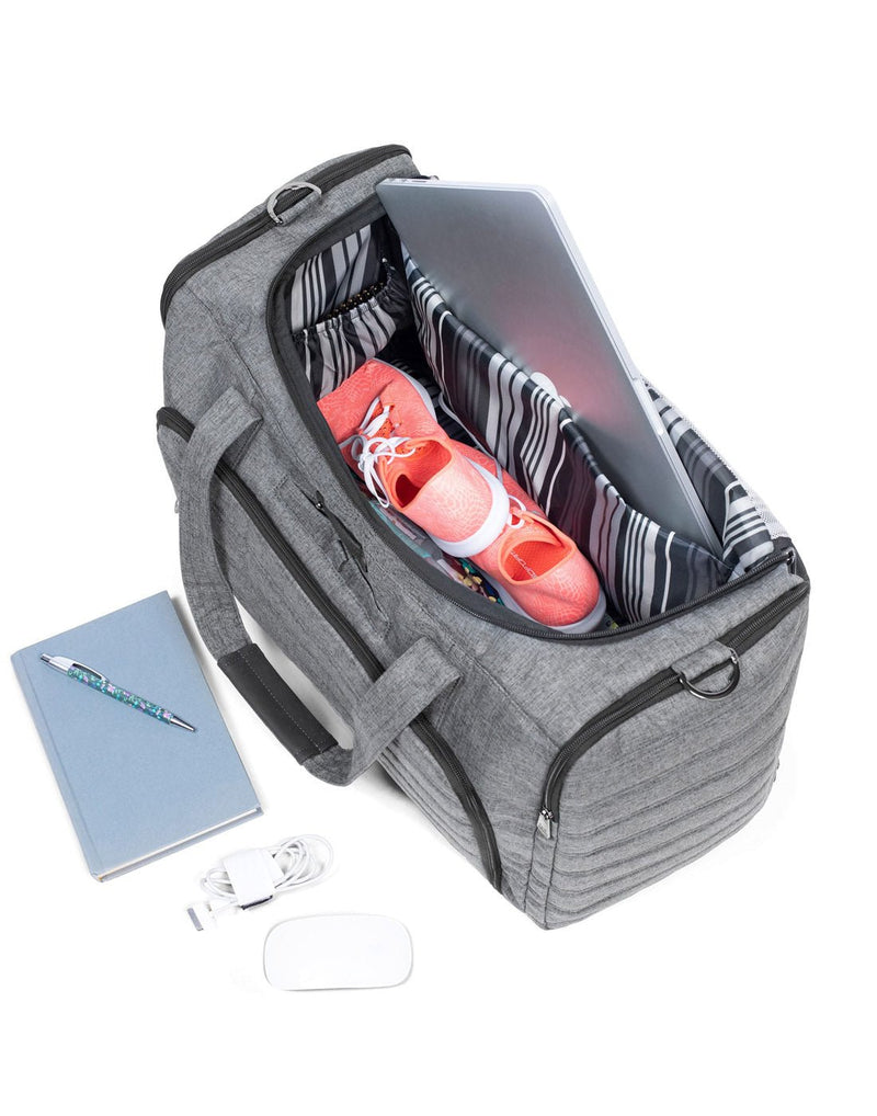 Lifestyle view of Lug Trolley Duffle Bag in heather grey with laptop and coral running shoes inside and notebook, pen, mouse and cord beside