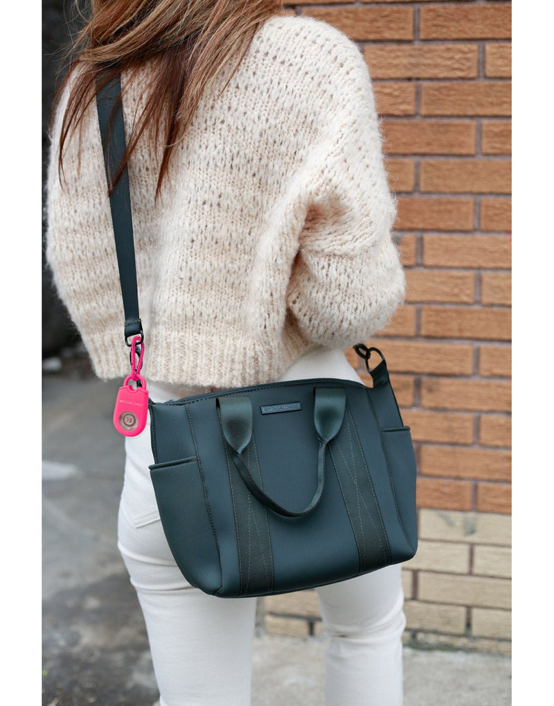 Lifestyle image of woman walking with the MyTagAlongs Personal Alarm attached to a black crossbody purse