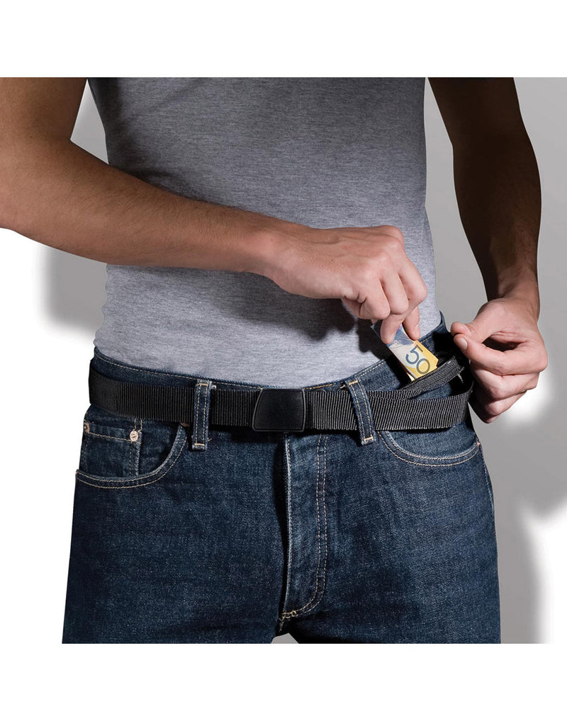 Close up of man's torso wearing grey t-shirt, blue jeans, and Pacsafe Cashsafe Anti-Theft Travel Wallet Belt, putting cash into the secret pocket