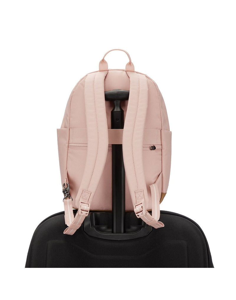 Pacsafe® Go 15L Anti-theft Backpack, sunset pink, back view sitting on top of a black luggage with handle through the back strap