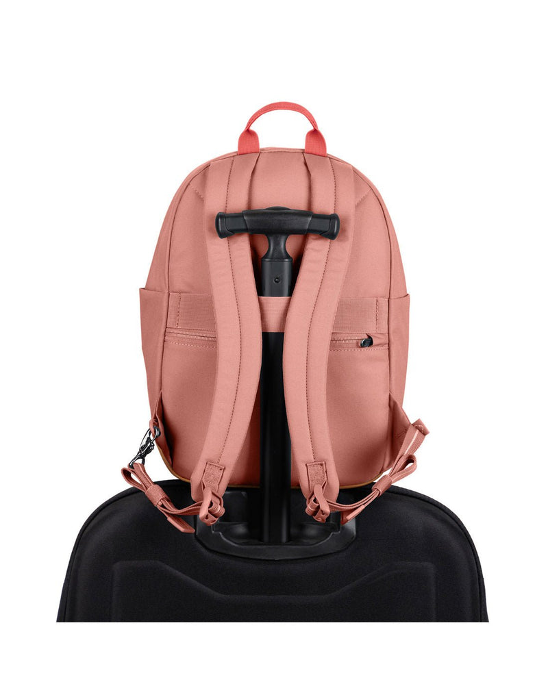 Pacsafe® Go 15L Anti-theft Backpack in rose colour secured onto the extended handle of a full sized wheeled luggage.