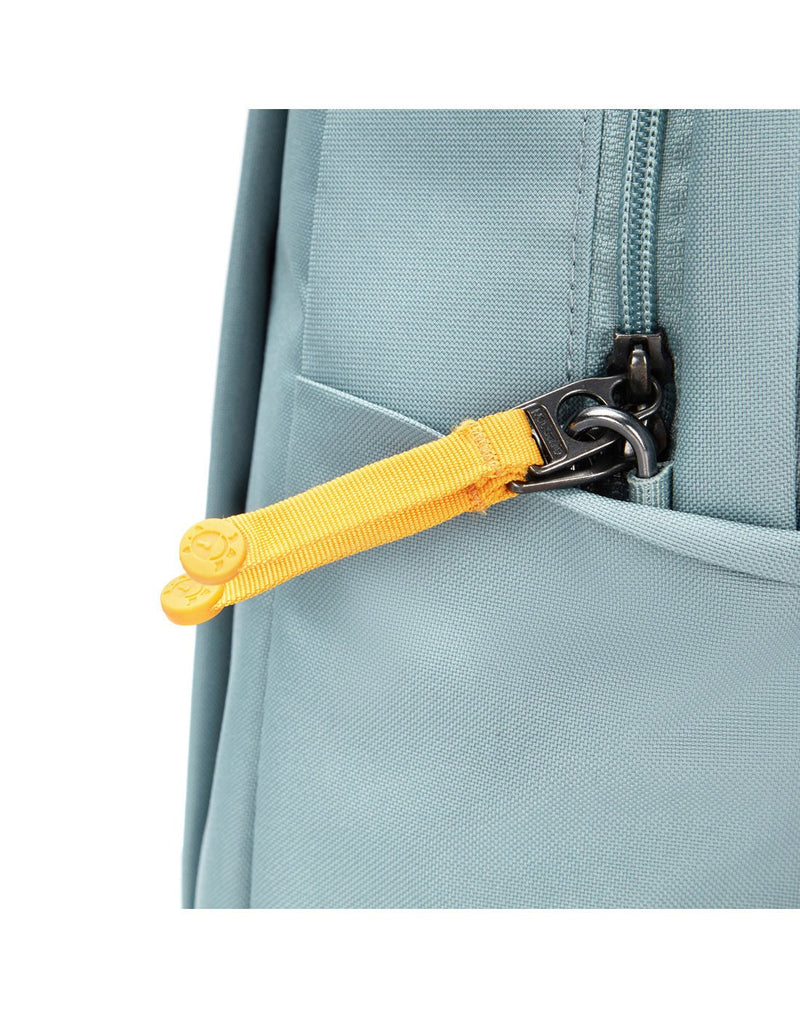 Close up of yellow zipper pulls on fresh mint backpack hooked with security clip
