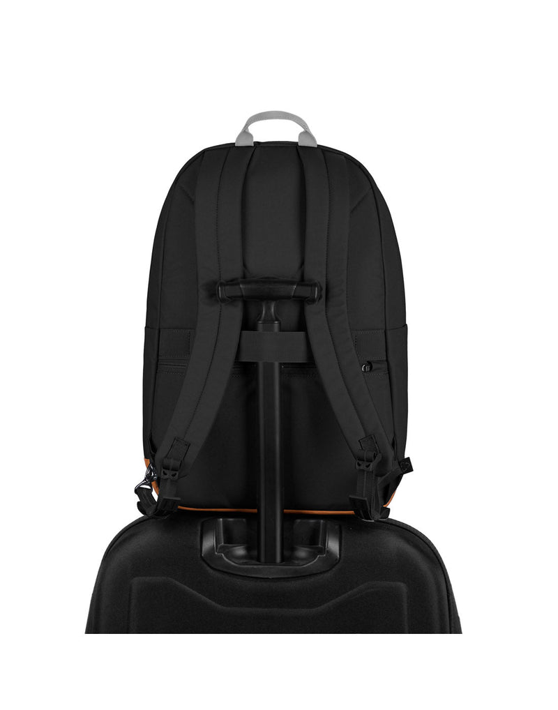 Pacsafe® Go 25L Anti-theft Backpack, jet black, back view sitting on top of a black luggage with handle through back strap