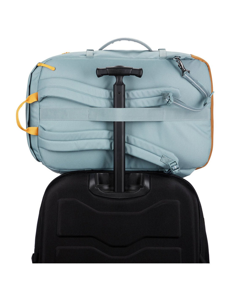 Backpack is secured onto the extended handle of a full sized wheeled luggage. 